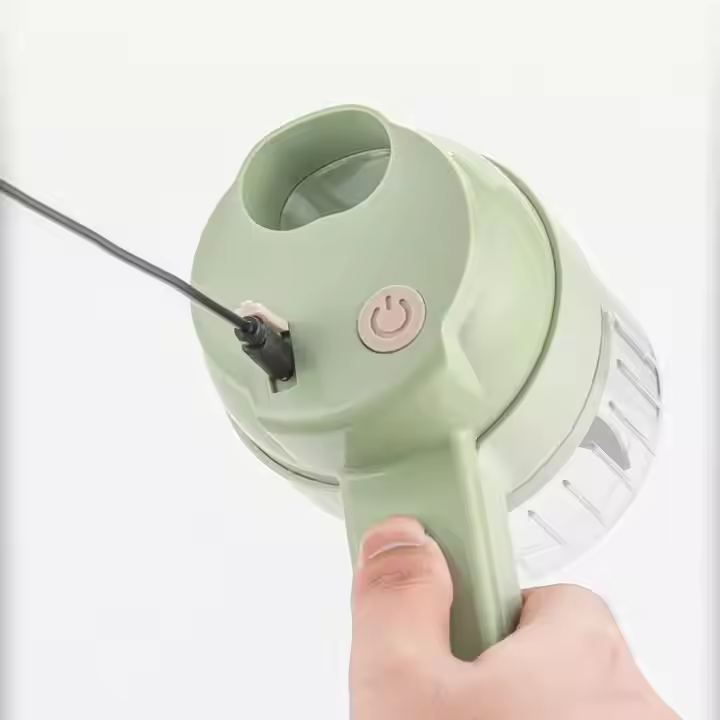 A hand holding a light green handheld vacuum cleaner against a plain white background, showing the top port and power button.